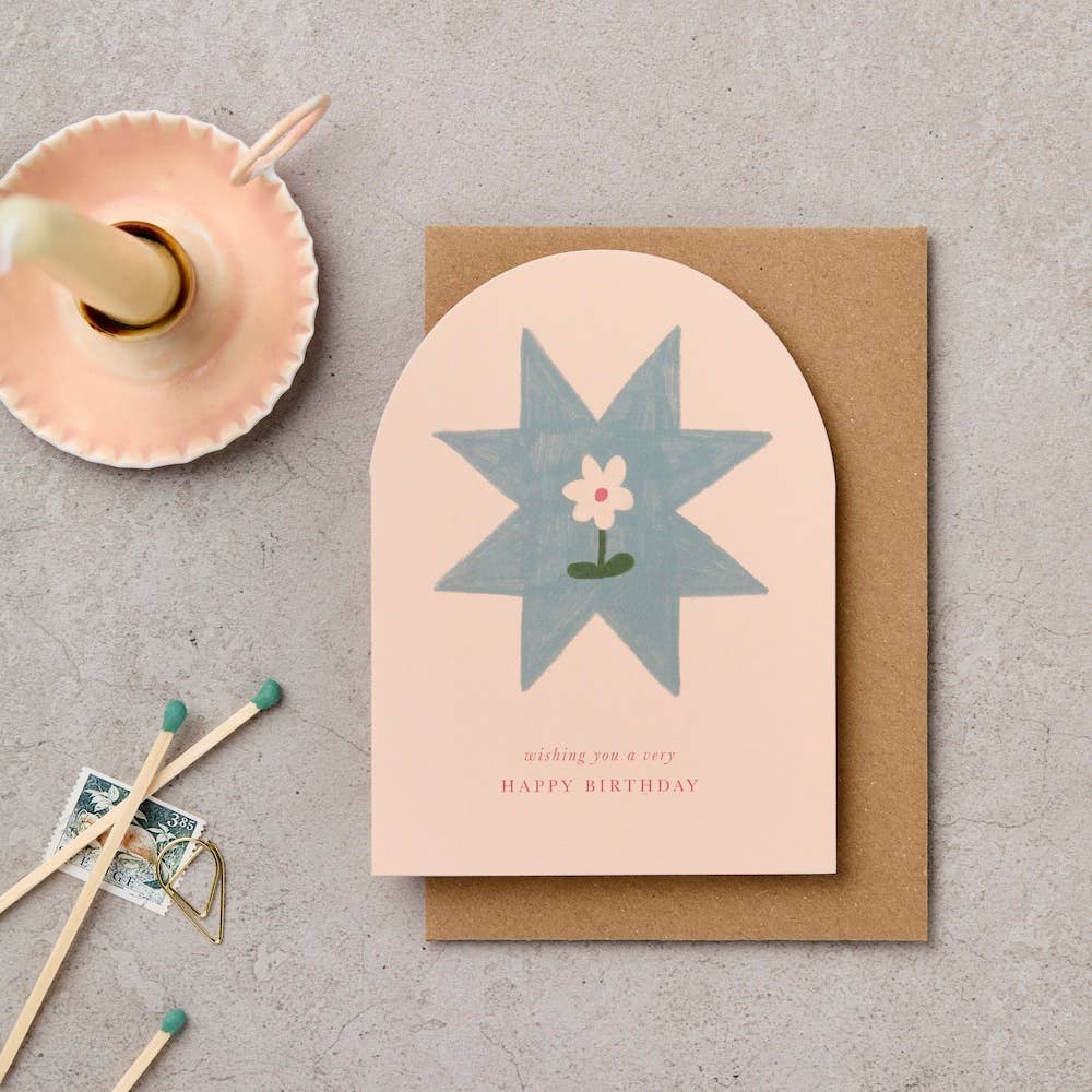 Greeting card with blue star design and 'Happy Birthday' text on a textured surface with matches and a small dish.