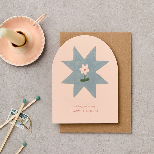 Greeting card with blue star design and 'Happy Birthday' text on a textured surface with matches and a small dish.