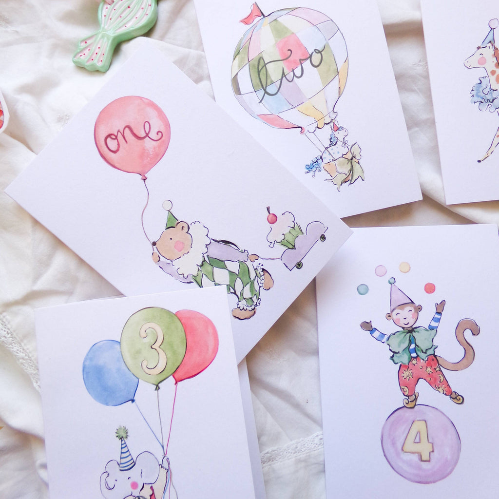 Set of birthday cards with cartoon monkey characters and balloons on a soft surface.