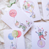 Set of birthday cards with cartoon monkey characters and balloons on a soft surface.