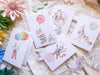 Set of children's cards with illustrations of a clown, balloon, and other decorative elements on a soft fabric background.