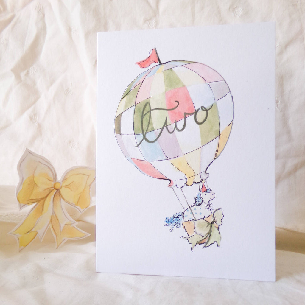 Greeting card with hot air balloon design and 'hello' text on a textured surface.