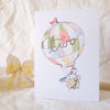 Greeting card with hot air balloon design and 'hello' text on a textured surface.