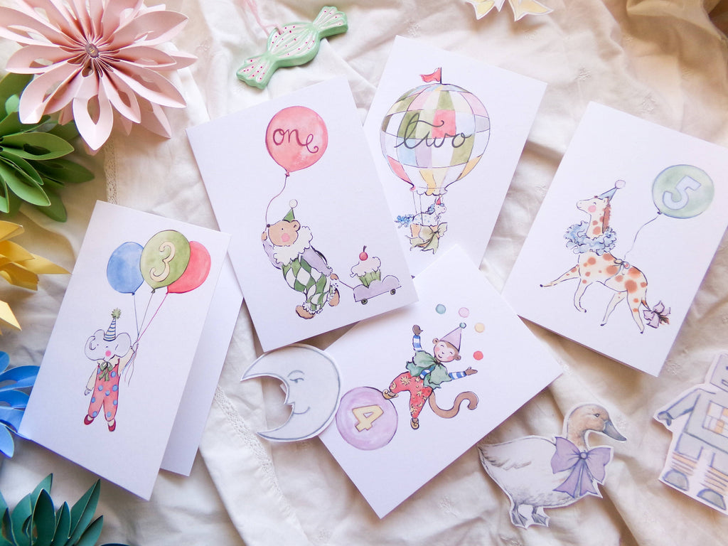 Set of children's cards with illustrations of a clown, balloon, and other decorative elements on a soft fabric background.