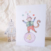 Children's birthday card with monkey juggling on a ball, robot, and number 4 on a soft fabric background.