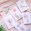 Set of children's birthday cards with colorful balloons and animals on a striped surface.