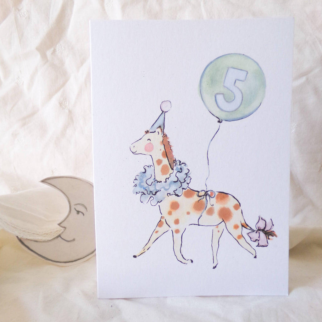 Children's birthday card with a giraffe wearing a party hat and holding a balloon with the number 5, on a soft white background.