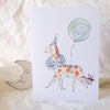 Children's birthday card with a giraffe wearing a party hat and holding a balloon with the number 5, on a soft white background.