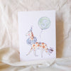 Card with a giraffe illustration and number 5 balloon on a beige fabric background