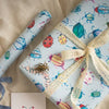 Gift wrapped in colorful bug-themed paper with a matching card on a matching background.