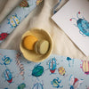 Colorful insect illustrations on paper and fabric with a small bowl of macarons.