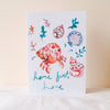 Card with a colorful crab and shell design on a light background
