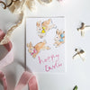 Easter card with bunnies and 'Happy Easter' text, surrounded by ribbons and decorative elements on a white background.