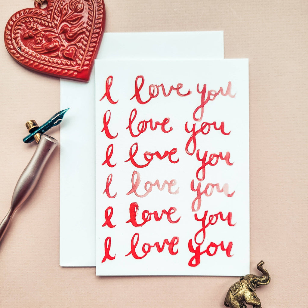 Card with 'I love you' text, heart-shaped object, and elephant figurine on a beige background