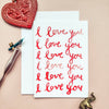 Card with 'I love you' text, heart-shaped object, and elephant figurine on a beige background