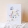 Greeting card with a design of a party hat and confetti on a white background