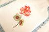Decorative pillow with embroidered red flowers on a beige background