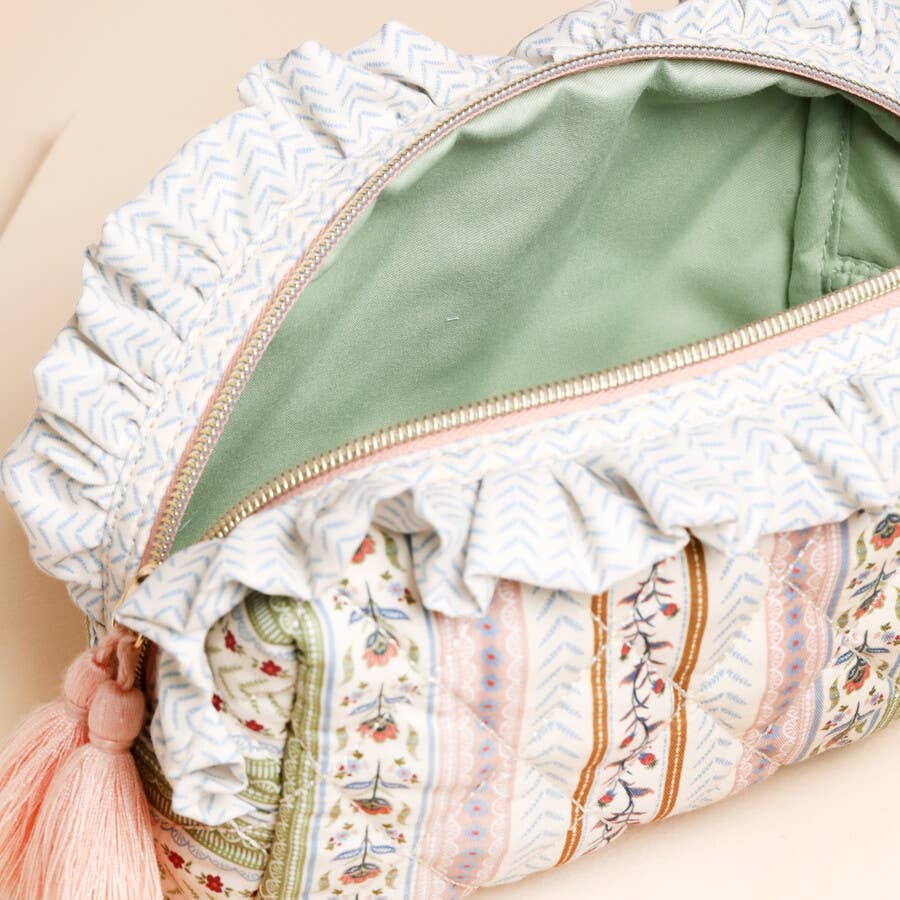 Patterned fabric pouch with ruffles and a tassel on a beige background