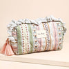 Decorative cylindrical pillow with ruffled top and tassels on a beige background