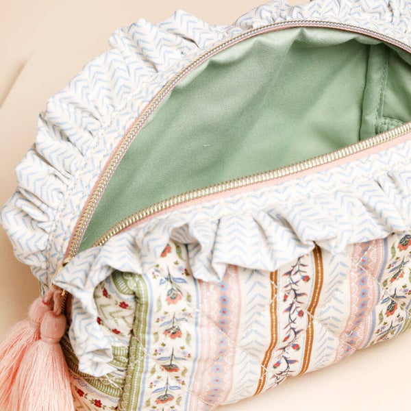 Patterned fabric pouch with ruffles and a tassel on a beige background