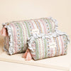 Decorative cylindrical pillows with floral patterns and tassels on a beige surface
