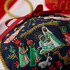 Embroidered Christmas ornament with nativity scene design on a red ribbon.