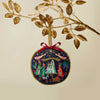 Decorative Christmas ornament with nativity scene design hanging from a branch.