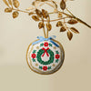 Decorative Christmas ornament with a wreath design hanging from a branch.