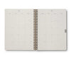 Open spiral-bound planner showing a monthly calendar layout on white background