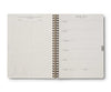 Open spiral-bound planner with daily schedule and calendar on white background
