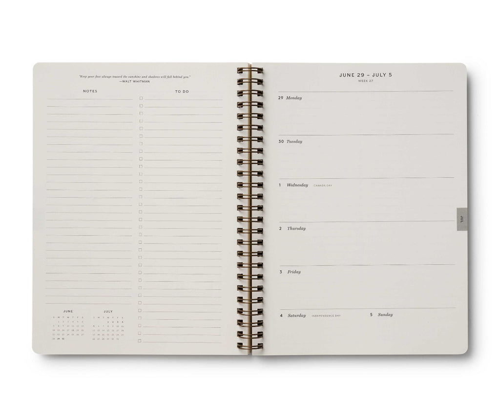 Open spiral-bound planner with daily schedule and calendar on white background