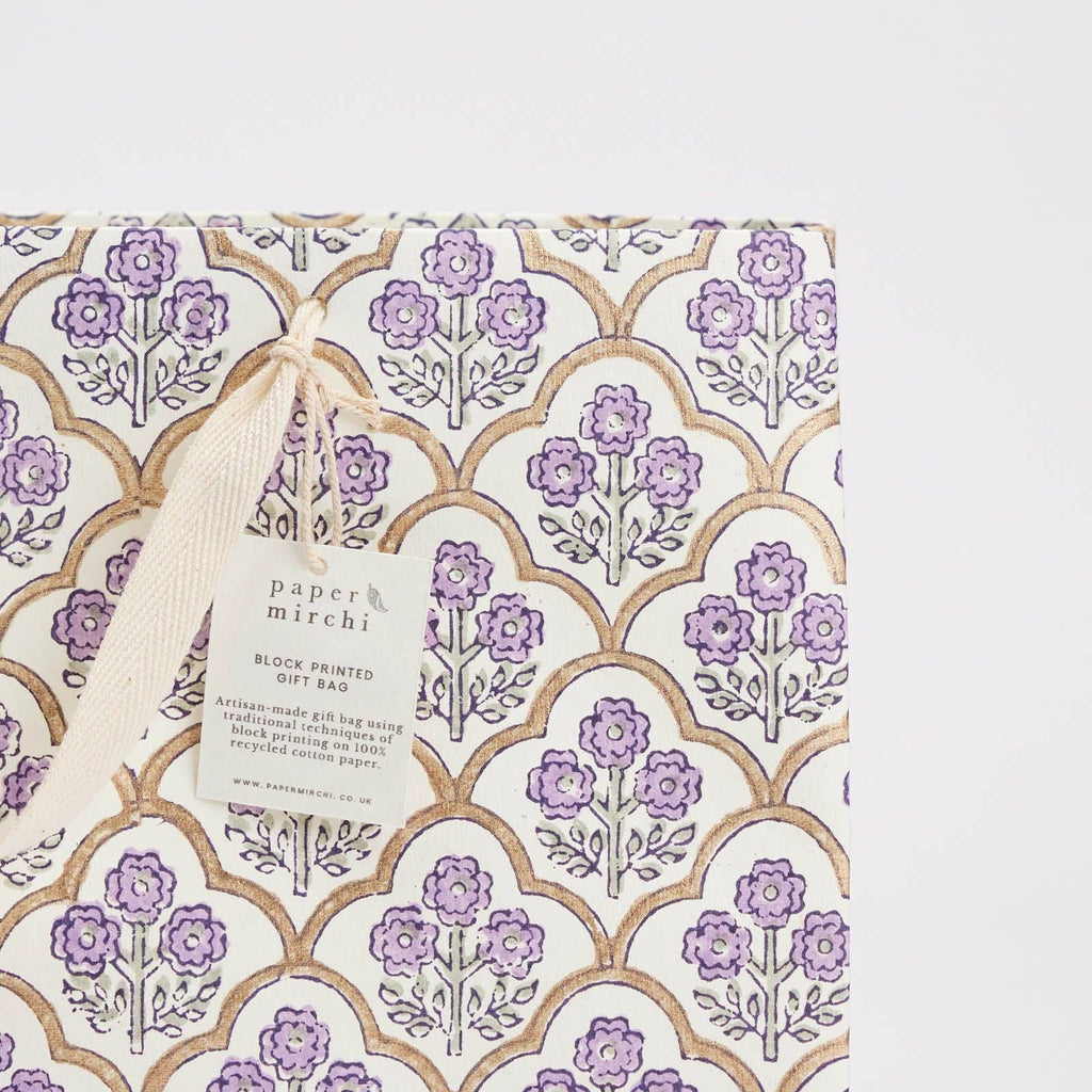 Gift bag with floral pattern and 'paper mirchi' tag on a light gray background