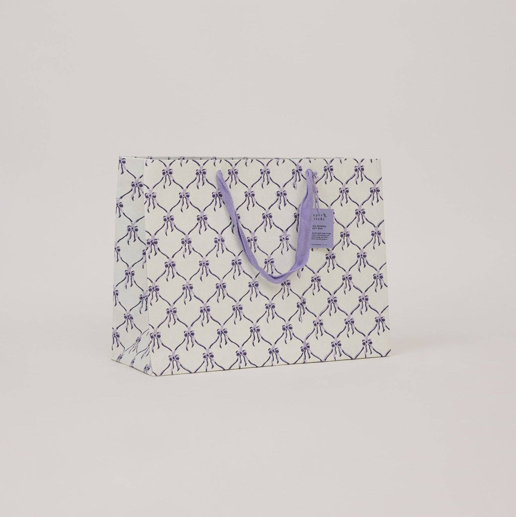 Reusable shopping bag with purple bow pattern on a light gray background