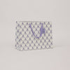 Reusable shopping bag with purple bow pattern on a light gray background