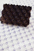Chocolate lace cake with intricate design on a textured white background
