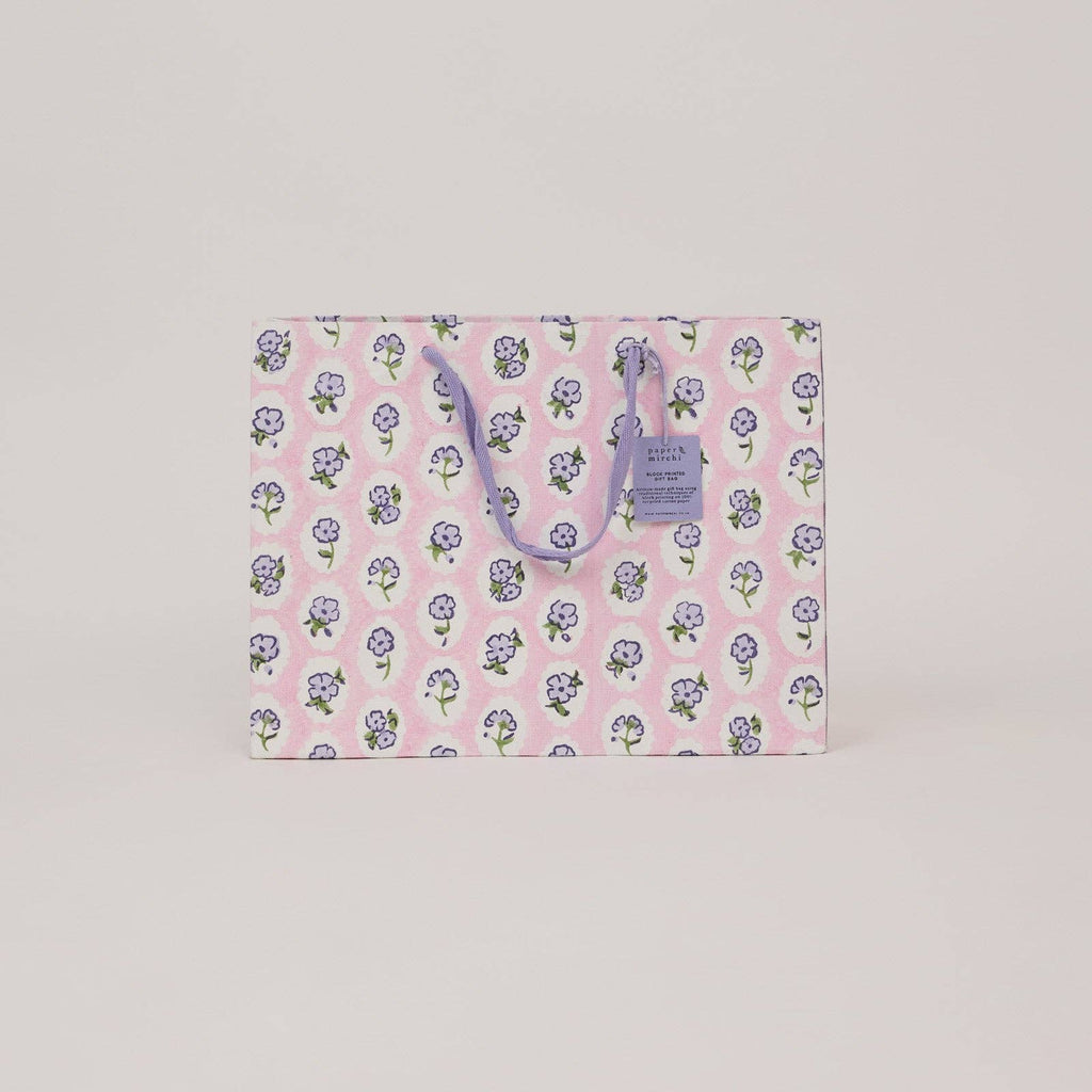 Floral-patterned paper bag with a visible brand tag on a light gray background