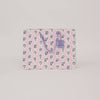 Floral-patterned paper bag with a visible brand tag on a light gray background