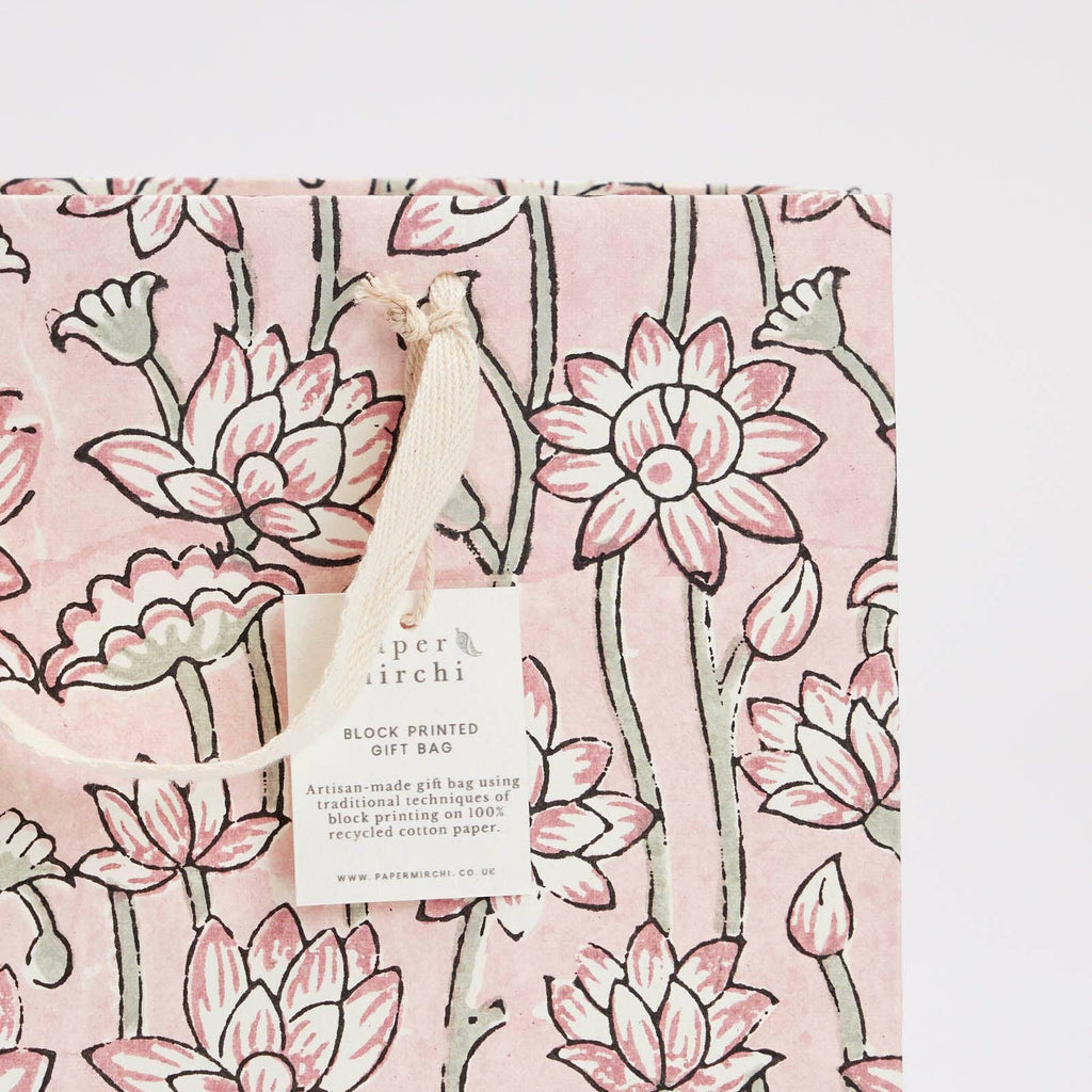 Gift bag with pink floral pattern and a visible brand tag on a matching pink background