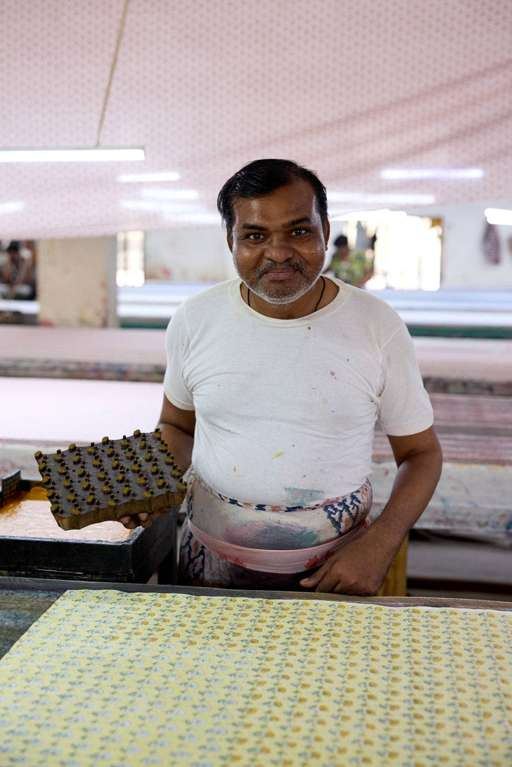 Man standing in a textile factory with fabric in front of him