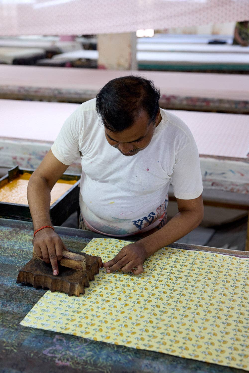 Person working with fabric and a printing tool in a textile factory.