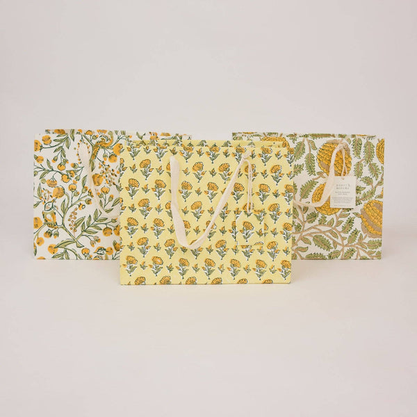 Set of three floral-patterned bags on a light gray background