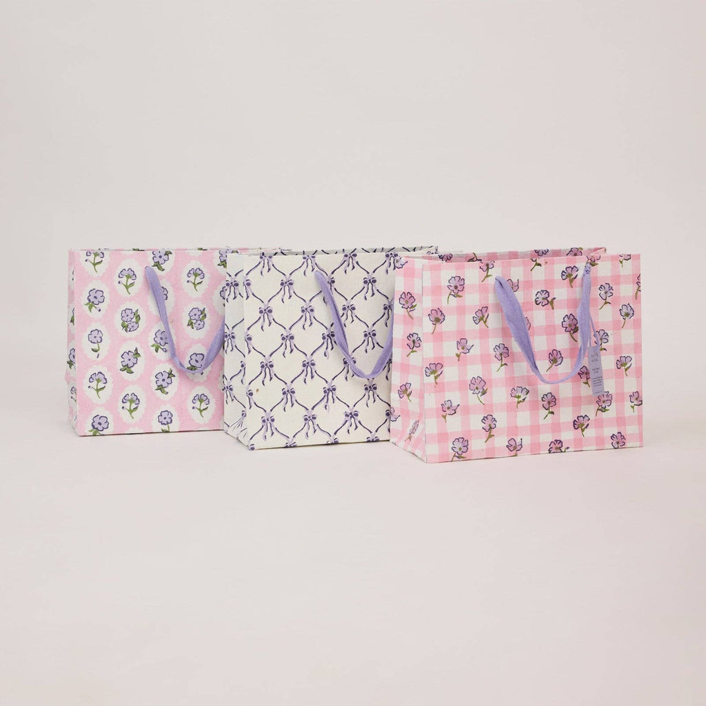 Two pink bags with floral and checkered patterns on a light gray background