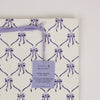 Block printed gift bag with purple bow pattern and 'paper mirchi' tag on a white background