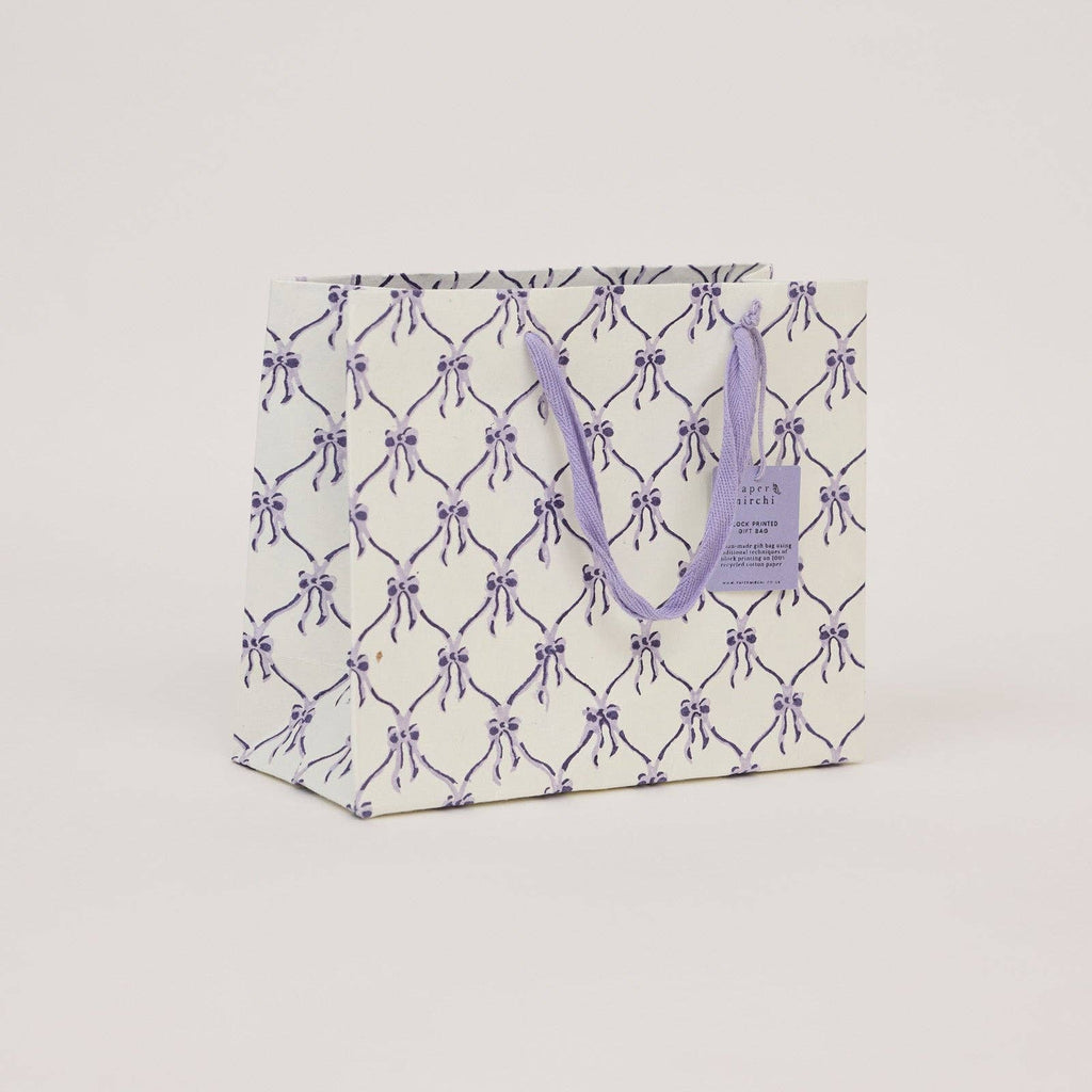 Gift bag with purple bow pattern on a light gray background