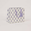 Gift bag with purple bow pattern on a light gray background
