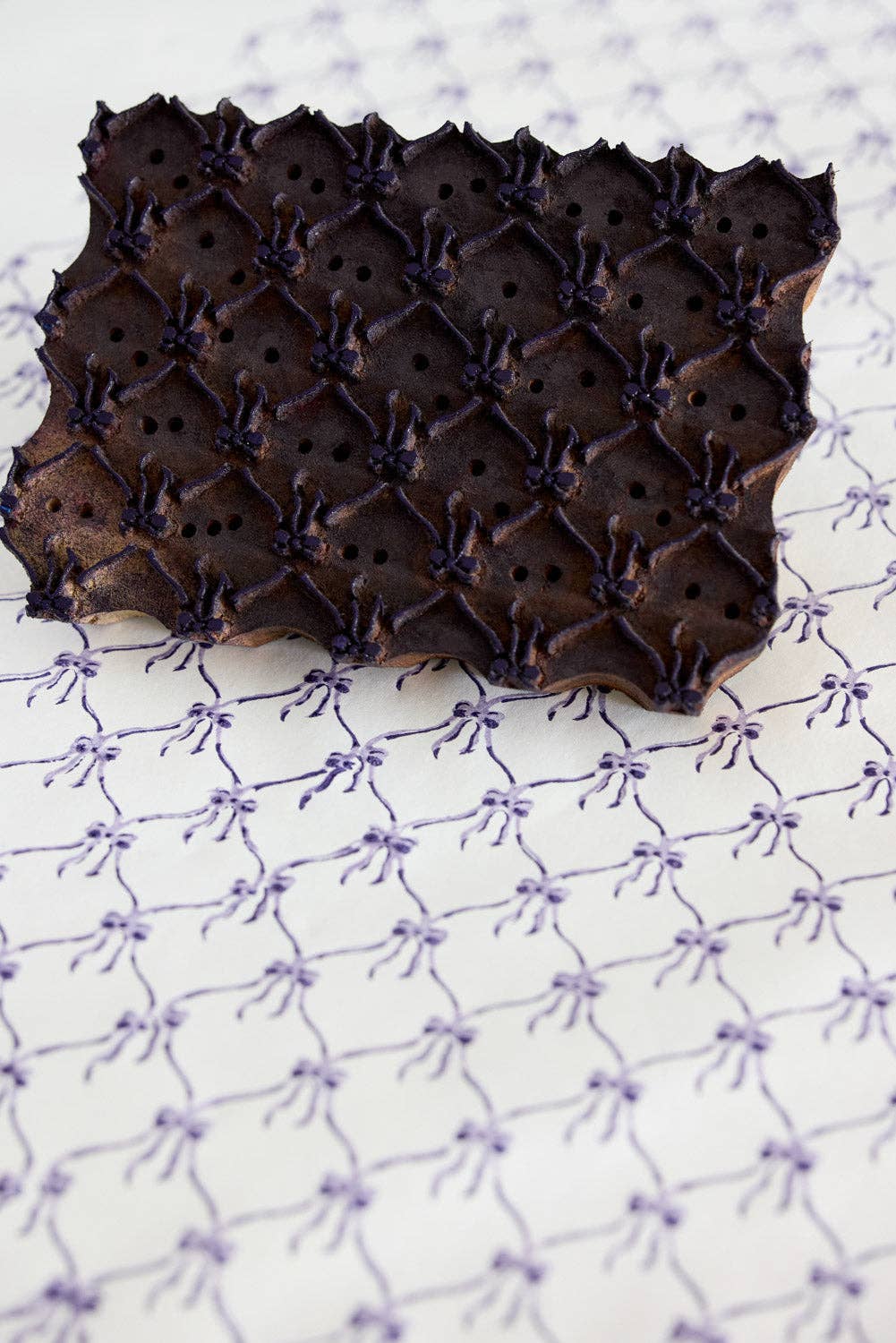 Chocolate lace cake with intricate design on a textured white background