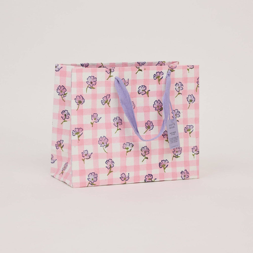 Floral and checkered patterned gift bag on a light pink background