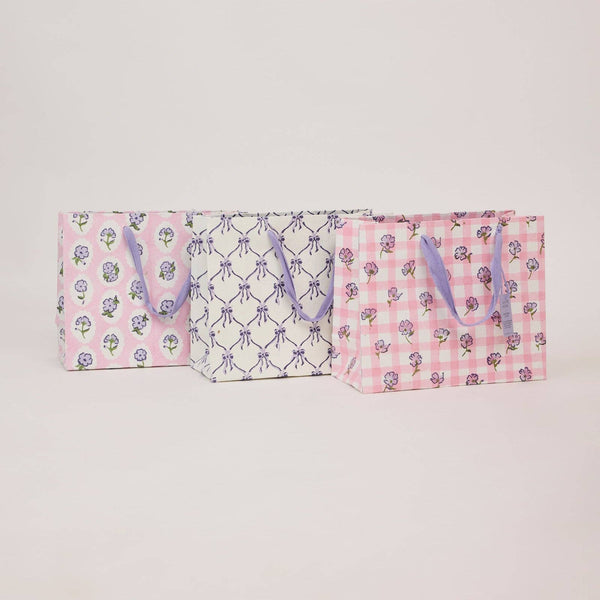 Two pink bags with floral and checkered patterns on a light gray background
