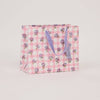 Floral and checkered patterned gift bag on a light pink background