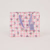 Floral-patterned bag with a purple handle on a light pink background